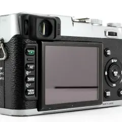 Tył aparatu Fujifilm X100S z widocznym ekranem, przyciskami sterującymi i pokrętłami.