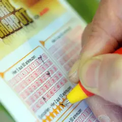 Prawda o rzekomych wróżbitach, którzy trafili liczby w Eurojackpot. Dłoń zaznacza liczby na kuponie lotto.