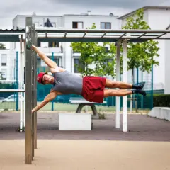 Mann hält die Flagge auf einem Calisthenics-Park. Das zeigt, was ist Calisthenics: Kraft, Balance und Körperbeherrschung.