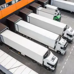 Ciężarówki czekają na załadunek przy magazynie. Logistyka między Francją a Polską kwitnie, zapewniając płynny transport towarów.
