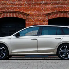 Złoty kombi Octavia 4 stoi na tle ceglanej ściany z dwoma łukowatymi oknami.