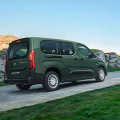 Zielony, używany Toyota Proace City Verso jedzie po krętej drodze wśród skał i zieleni.