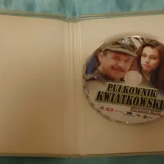 Płyta DVD z filmem "Pułkownik Kwiatkowski" i jego obsadą. Widoczni są główni bohaterowie, pułkownik i młoda kobieta.