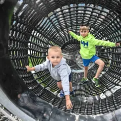 Dwóch chłopców bawi się w tunelu z lin, który jest częścią ścieżki w chmurach na Słowacji.