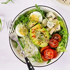 Deliciosa ensalada de aguacate con huevo cocido, queso azul, tomates cherry, brotes y arroz blanco.