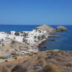 Vista panorámica de la **isleta del Moro, Almería**, con casas blancas, barcas y el mar azul.