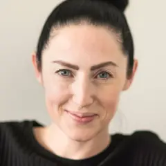 Emma Gray Munthe, med håret uppsatt i en knut, ler mot kameran. Hon bär en svart, ribbad tröja.