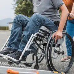 Osoba na wózku inwalidzkim wjeżdża na rampę. Kto otrzyma świadczenie wspierające? Osoby z niepełnosprawnościami.