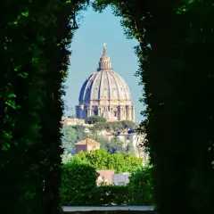 Blick durch grüne Hecken auf die Kuppel des Petersdoms. Ein versteckter Aussichtspunkt, einer der vielen Rom Geheimtipps.