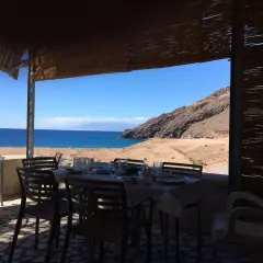 Mesas puestas en restaurantes en La Fabriquilla, Cabo de Gata, con vistas al mar y a la montaña.