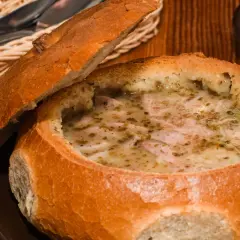 Gorący żur śląski podany w chlebie, z kawałkami kiełbasy i przyprawami. Idealny na chłodne dni.