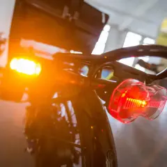 Blinker am Fahrrad leuchten orange und rot. Das Rücklicht ist klar erkennbar, während das vordere Licht diffus strahlt.