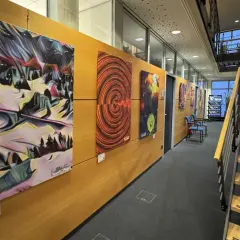 Moderne Kunstwerke schmücken die Wand einer Galerie in Bergisch Gladbach. Eine Treppe führt nach oben.
