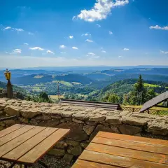 Widok z góry Sowa na malownicze wzgórza. Drewniane stoły i kamienny murek zapraszają do podziwiania panoramy.