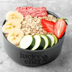 Zutaten für ein hundekekse rezept: Hackfleisch, Haferflocken, Bananenscheiben, Erdbeeren und Zucchinirad.