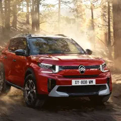 Röd Citroën C3 Aircross testkörs på en dammig skogsväg i solnedgången.