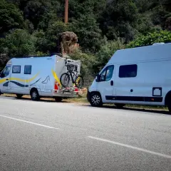 Trzy kampery zaparkowane przy drodze na Korsyce. Jeden z nich ma rower na bagażniku.