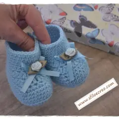 Delicate babbucce uncinetto azzurre, decorate con fiocchi e rose, perfette per un neonato. Trova schemi gratis per crearle!
