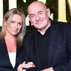 Marcin Daniec z żoną na tle złotych liter i zielonej ściany.