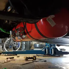 Installation d'un réservoir GPL sous un camping-car, respectant la réglementation GPL camping-car. Le réservoir rouge est visible, fixé sous le châssis.