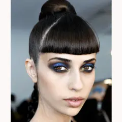 Occhi intensi con smokey eyes blu elettrico e nero, capelli raccolti in uno chignon e treccia.