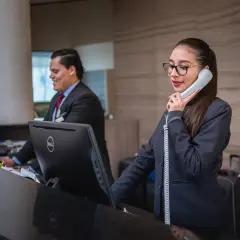 Recepcjonistka rozmawia przez telefon, podczas gdy jej kolega pracuje przy komputerze. Czy finloan dzwoni do pracodawcy?