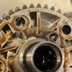 Widok z bliska na koła zmiennych faz rozrządu, z widocznymi elementami mechanicznymi i śladami oleju.