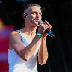 Vito Bambino na scenie, w białej podkoszulce, z mikrofonem w dłoni. Jego wzrost robi wrażenie.