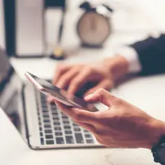 Biznesmen korzysta z telefonu i laptopa, planując przelewy Millenium.