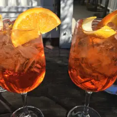 Dwa orzeźwiające aperitif z pomarańczą i skórką cytryny, idealne na letnie popołudnie.