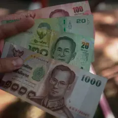 Ręka trzyma tajskie banknoty: 1000, 100, 20 bahtów. Planujesz podróż i zastanawiasz się, jakie dolary do Tajlandii zabrać? Lepiej wymienić na bahty.