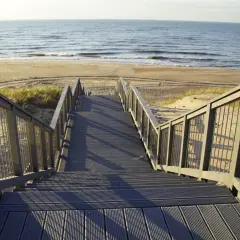 Schody prowadzące na plażę w Darłówku. Promenada z widokiem na morze i piasek.