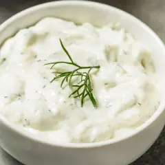 Salsa yogurt ricetta cremosa con aneto fresco e una fetta di limone sullo sfondo.