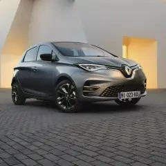 Une Renault Zoe grise, symbole de la mobilité électrique et de son autonomie, se gare devant une architecture moderne aux lignes épurées.