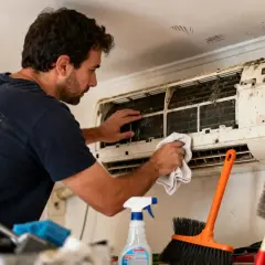 Un homme nettoie une climatisation très sale. L'entretien climatisation locataire est essentiel pour la santé.