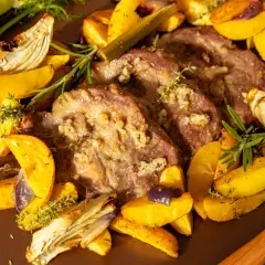 Saftiges Schweinesteak im Backofen ohne Anbraten, umgeben von goldbraunen Kartoffelspalten, Fenchel und Kräutern.