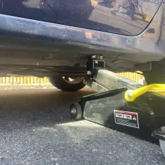 Lewarek podłożony pod wzmocnienie progu samochodu. Widać podnośnik i miejsce, gdzie podłożyć lewarek, by bezpiecznie podnieść auto.