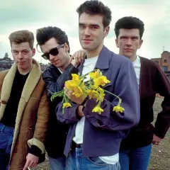 Członkowie The Smiths pozują z bukietem żółtych żonkili na tle postindustrialnego krajobrazu.