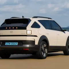 Kremowy Hyundai Nexo na plaży, z widokiem na morze i wyspę w oddali.