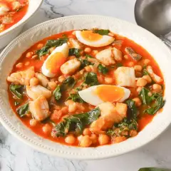 Un reconfortante potaje de vigilia con garbanzos, espinacas y trozos de pescado blanco, coronado con huevos duros.