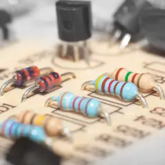 Na płytce drukowanej widoczne są elementy elektroniczne, w tym dioda zenera z kolorowymi paskami.