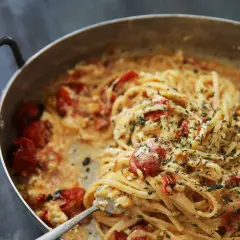 Pâtes crémeuses aux tomates cerises et herbes fraîches, servies dans une poêle. Un délice !