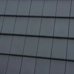 Zbliżenie na ciemnoszare dachówki ułożone w rzędy.