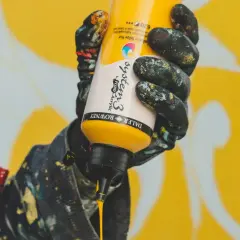 Mano con guanti sporchi di vernice che stringe un flacone di giallo brillante, pronto a creare un'opera d'arte. Il colore viola è assente, ma l'energia creativa è palpabile.
