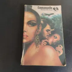 Okładka książki "Emmanuelle" z wizerunkiem kobiety i pary, w tle samolot i dżungla.