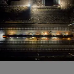 Pociąg mknie po torach, a jego główka szyny iskrzy w noc.