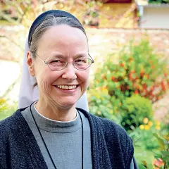 Lächelnde evangelische Nonne mit Brille im Garten.