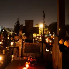 Nocny cmentarz 2 listopada, dzień zaduszny. Płonące znicze i kwiaty na grobach tworzą magiczny, choć melancholijny nastrój.