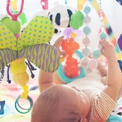 En bebis leker under en färgglad babygym med en söt kanin som hänger.