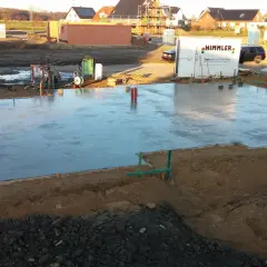 Frisch gegossene Betonplatte auf einer Baustelle. Verschiedene Arten von Bewehrung sind sichtbar, die für Stabilität sorgen.